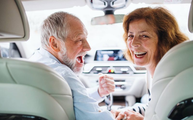 rear-view-of-happy-senior-couple-sitting-in-car-looking-back.jpg